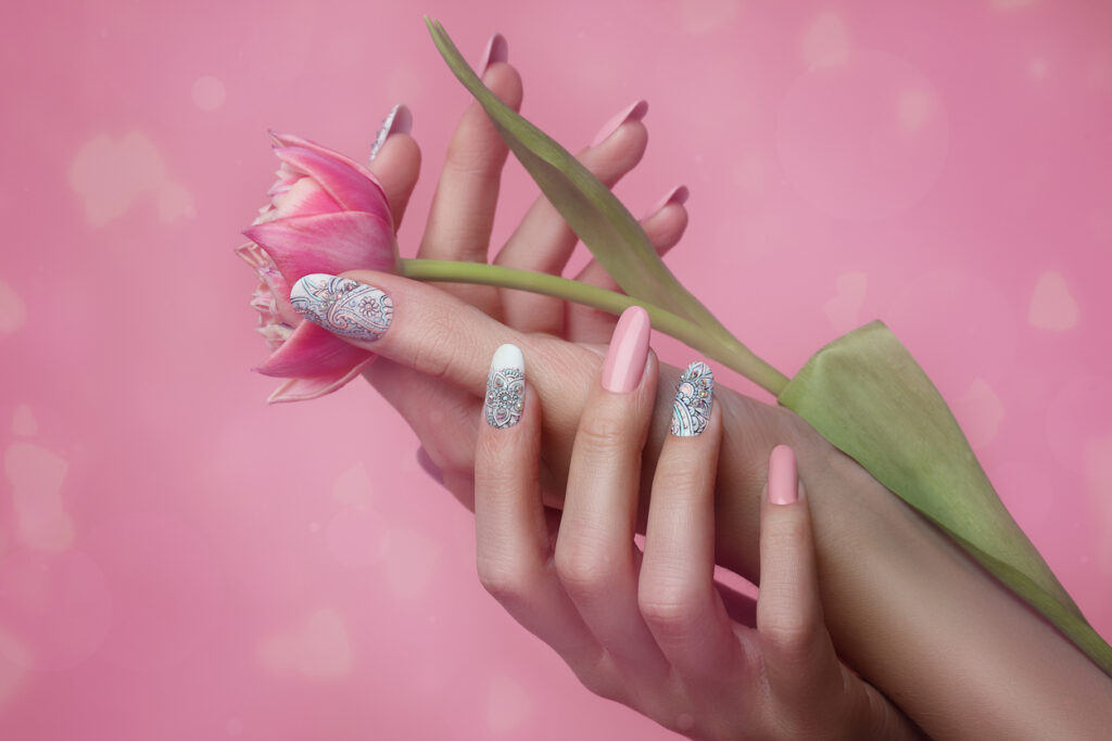 Nails Art Design. Hands With pink Manicure On pink Background. Close Up Of Female Hands With Trendy pink Nails with spring flower.